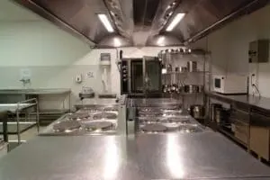 How Much Does It Cost to Install a Kitchen Hood in a Restaurant? - Ambient Edge gleaming restaurant kitchen with large hoods suspended over cooktop