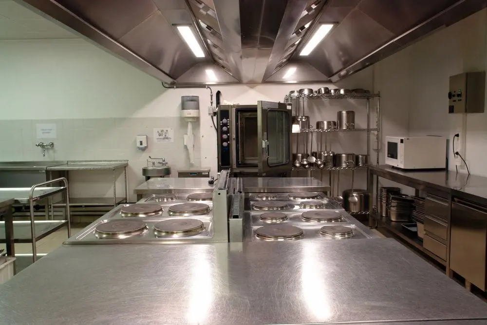 gleaming restaurant kitchen with large hoods suspended over cooktop