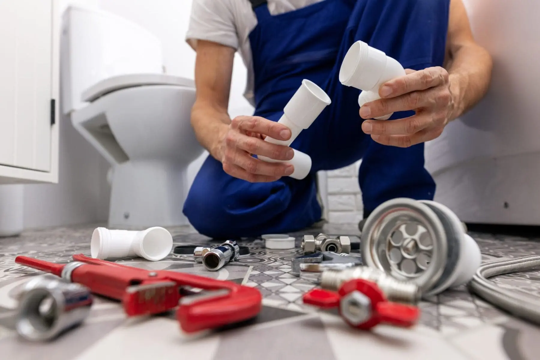 plumber on floor looking at plumbing parts