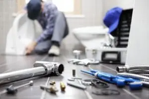 tools on ground with a plumber in the background