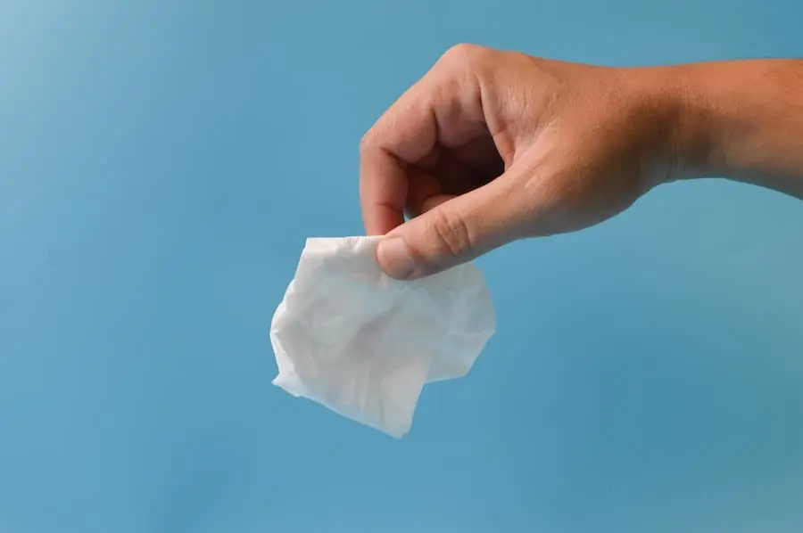 Hand holding crumpled tissue paper isolated on a blue background