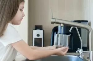 child washing hands in a kitchen sink