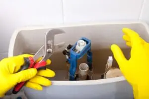 person with rubber gloves fixing a toilet