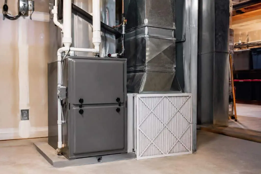 Residential air handler with ductwork and a pleated HVAC filter positioned beside the unit