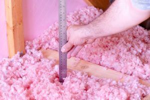 A man checks the level of insulation with a ruler
