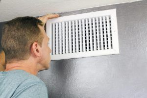 man checking air duct in home