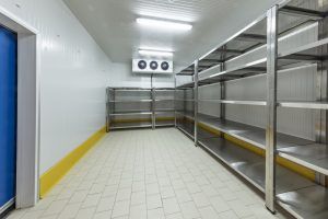 empty walk-in freezer with metal shelves and condensing unit