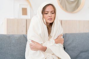 woman sitting on couch and bundled up in blanket