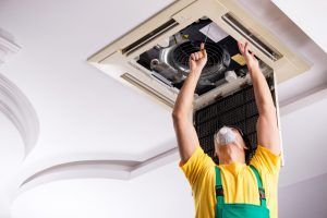 repairman inspects part of hvac system in ceiling