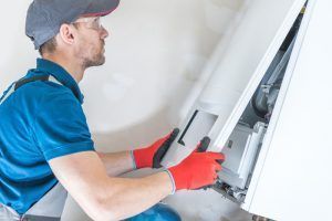technician fixes heating unit in home