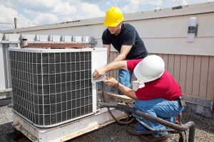 technicians repair ac unit on health facility rooftop