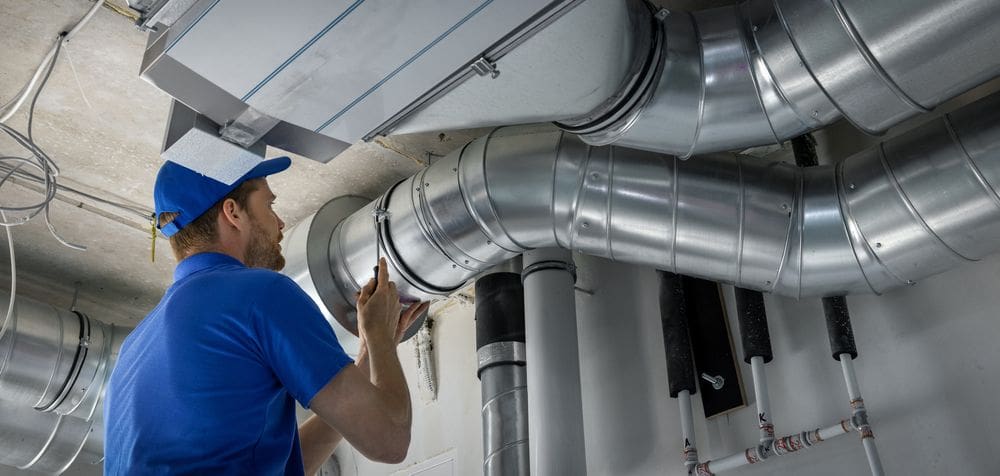 HVAC worker installing pipe ducts