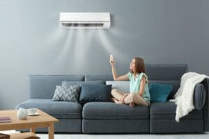 young woman switching on air conditioner