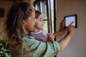 mother and child adjusting thermostat
