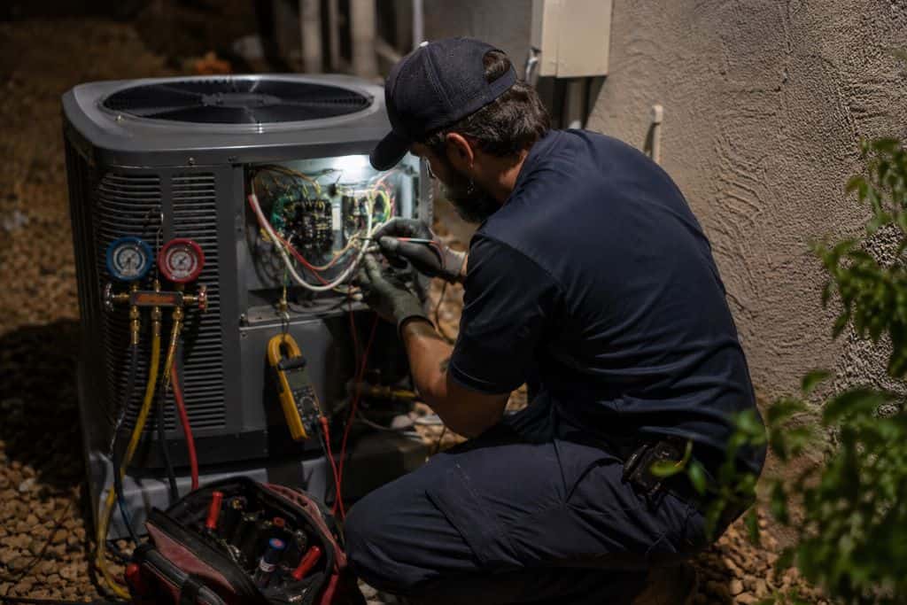 HVAC technician testing an open condenser for Emergency Air Conditioning Repair Services in Henderson NV